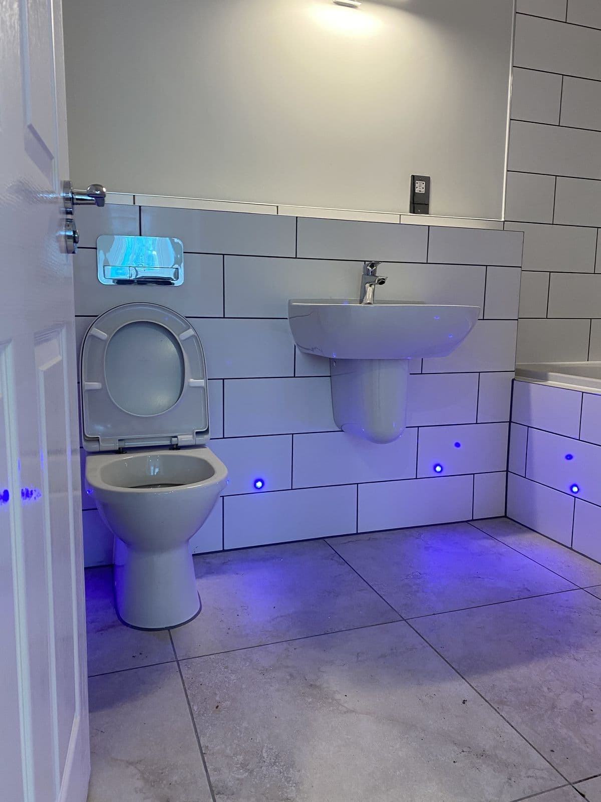 White metro-tiled bathroom with basin, toilet and LED plinth lights